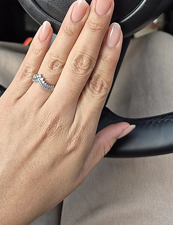 Mano de una clienta con uñas almendradas en nude natural y un anillo plateado.